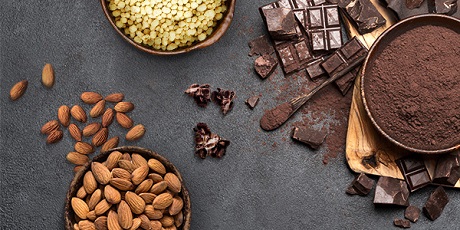 Ingredienti in ciotole su un tavolo. Mandorle, fave di cacao, pezzi di cioccolato e cacao in polvere.